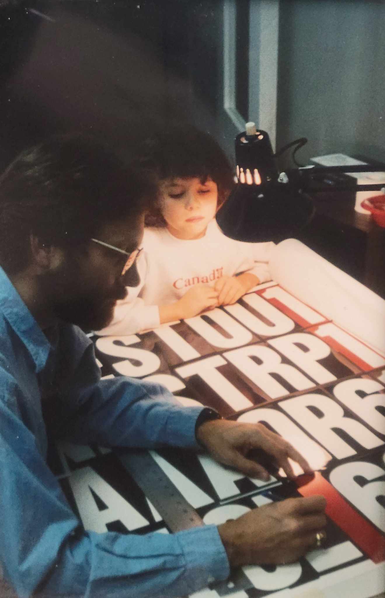 Young Claire looks on as her Dad, Rick, examines a film for screenprinting. A photo from a local newspaper, circa 1994-1995