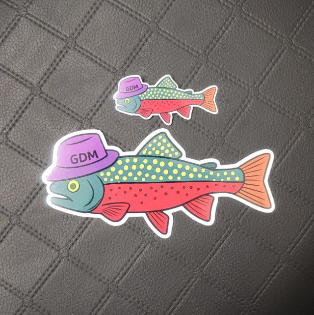 Premium die cut vinyl stickers with two vibrant fish in purple GDM hats; custom edges, two sizes on dark diamond-pattern. Printed for Good Days Marina