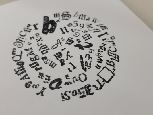 Letterpress print features a black and white circle of mixed fonts, symbols, and numbers on white paper; LIMITED RUN by Claire Davis.