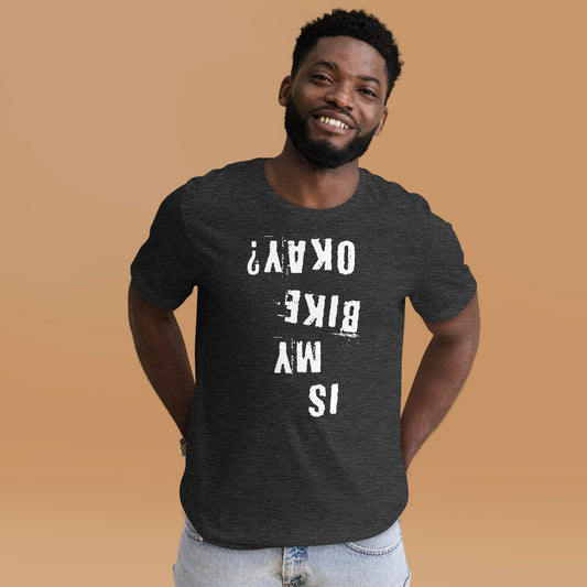 A man wears a dark gray InkBird “Is My Bike Okay?” cotton t-shirt with bold upside-down white text, perfect for mountain bikers.