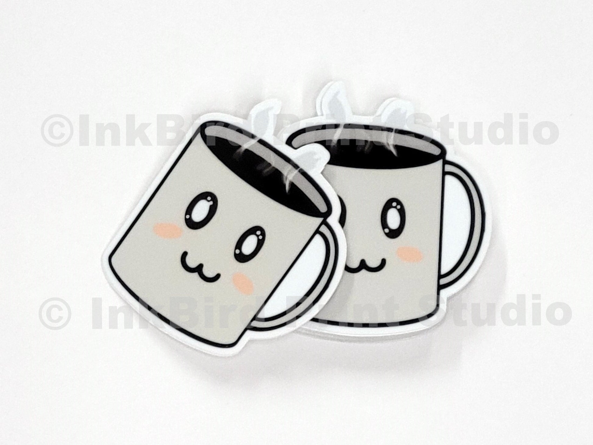 Vinyl coffee cup sticker by InkBird Print Studio with two cartoon mugs, rosy cheeks, clinking, and steamy details; die-cut, adhesive-backed.
